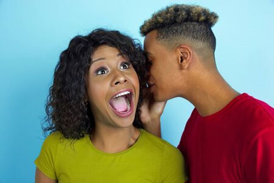 man whispering in woman s ear
