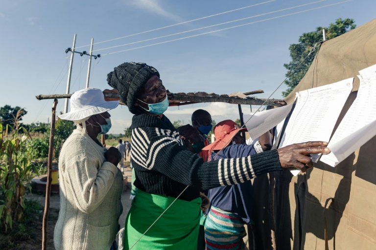 A voter checks for her name on the voters roll pinned outside a polling station in Epworth township